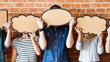 Three people stand with cardboard covering their faces.